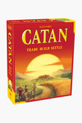 The Catan Studio strategy game box displays an illustrated landscape with fields, settlers, and a setting sun. The cover text reads "Catan: Trade Build Settle.