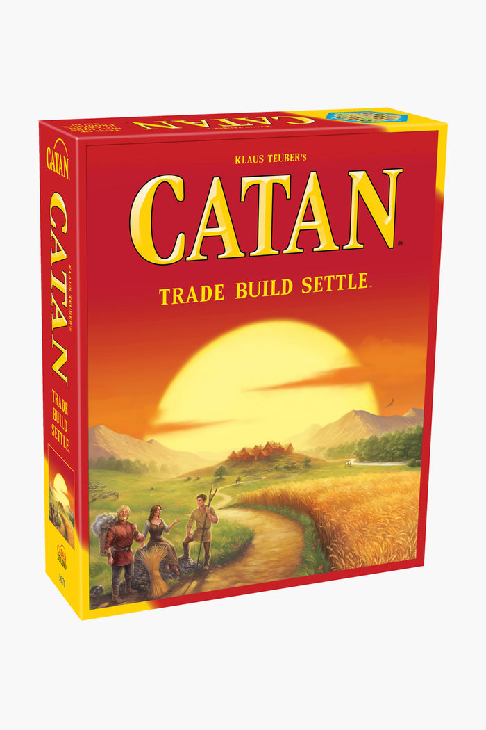 The Catan Studio strategy game box displays an illustrated landscape with fields, settlers, and a setting sun. The cover text reads "Catan: Trade Build Settle.
