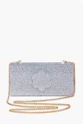 The ASHA Silver Sparkle Flower Clutch is a rectangular bag with a gold chain strap, dazzling glitter, and floral accents.