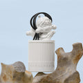 Decorative Pop Mart candle with a white base and black cord on a light blue background