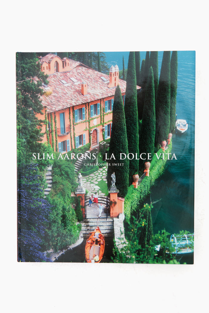 Book cover of Slim Aarons: La Dolce Vita by Christopher Sweet, published by Abrams Books, features a lakeside villa with a boat and tall cypress trees.