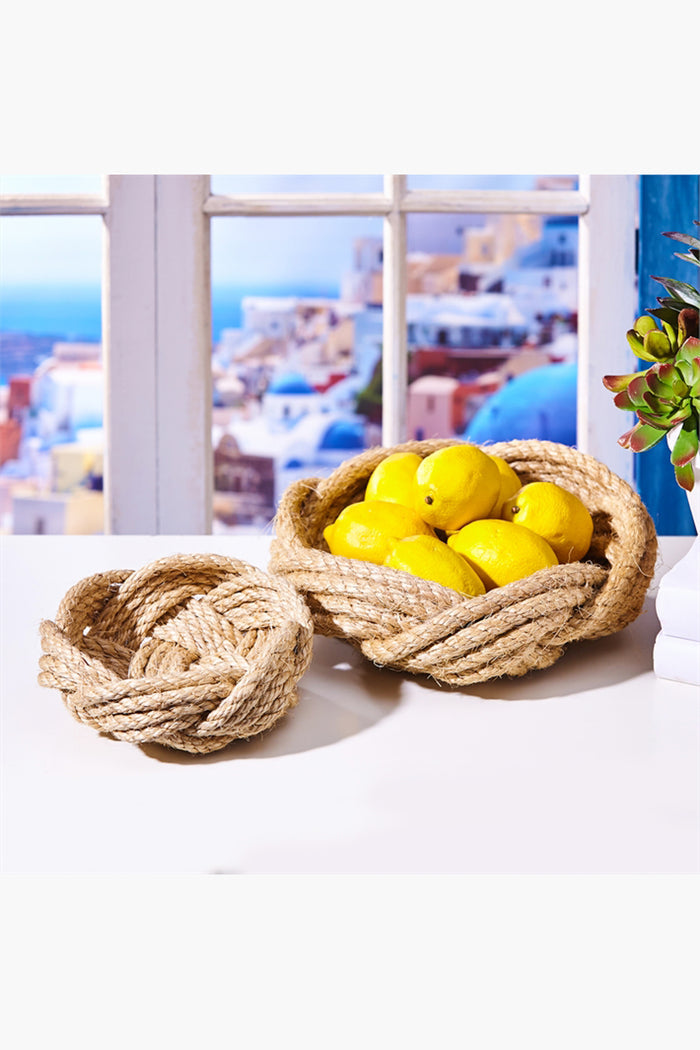 Two’s Company hand-woven rope baskets rest on a white table; one is filled with yellow lemons while the other remains empty, creating a nautical decor accent.