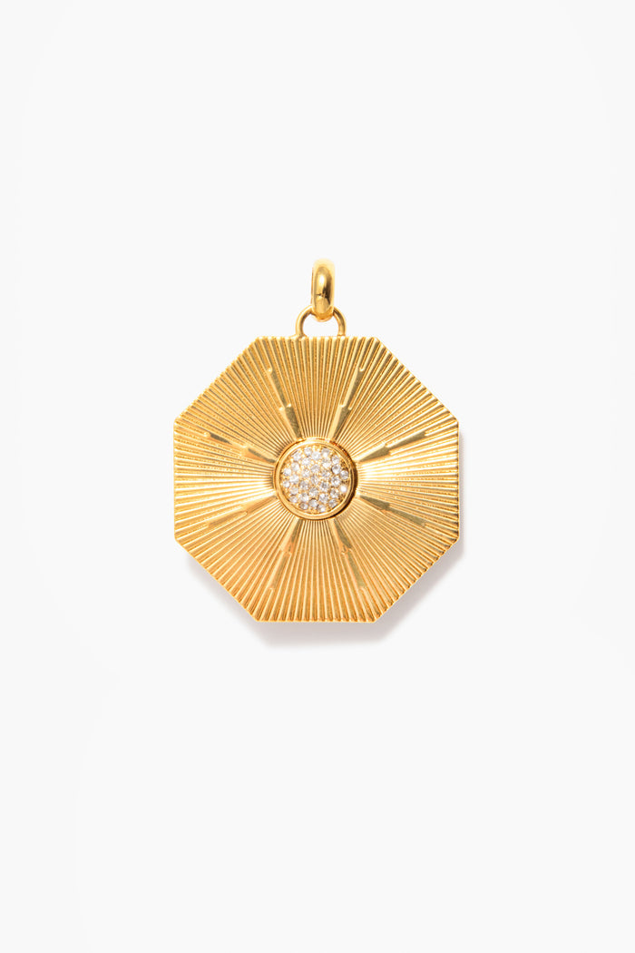 Tuckernuck Jewelry's Soleil Medallion necklace features an octagonal gold pendant with a textured, radiating pattern and a central cluster of small round white stones.