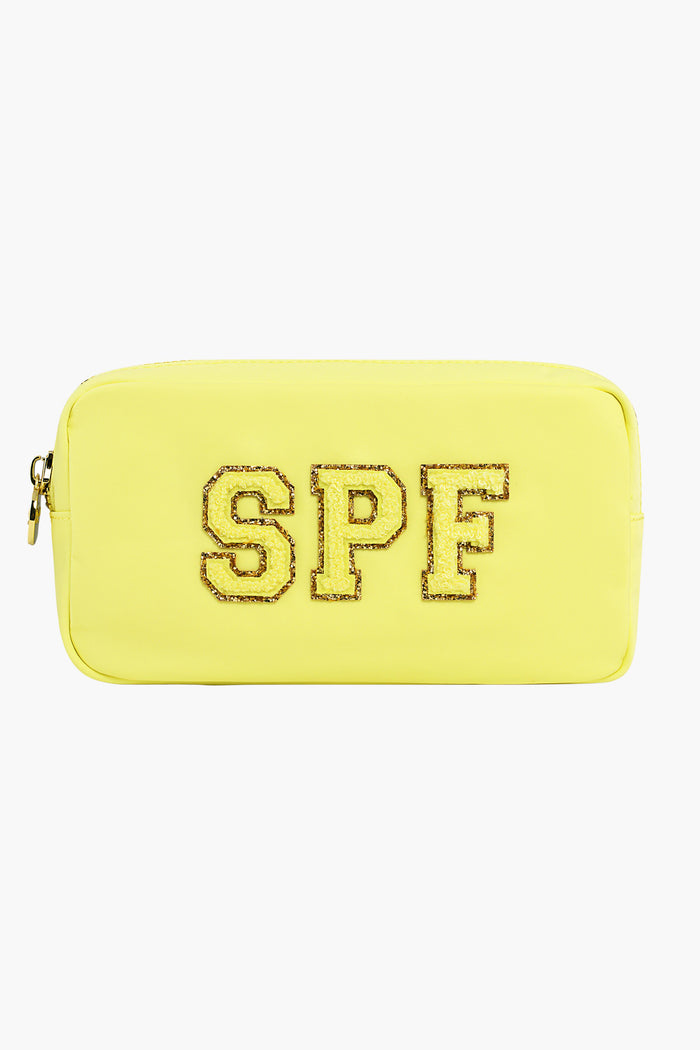 The Stoney Clover Lane rectangular yellow toiletry bag features a zipper and glittery gold-outlined SPF letters on the front—ideal for carrying your travel accessories.