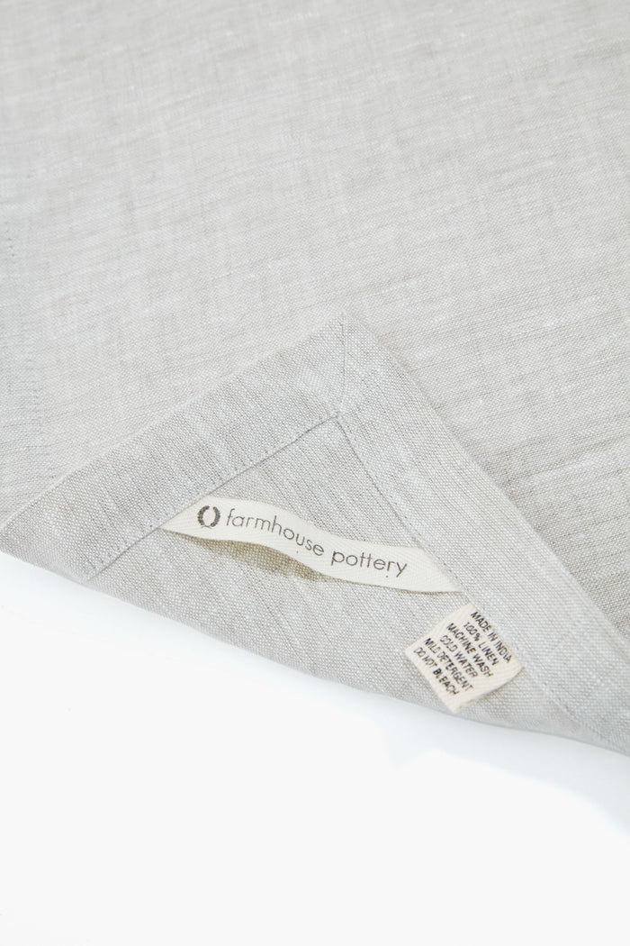 Stone Washed Linen Napkins from Farmhouse Pottery, classic and effortlessly chic, showcasing a folded corner and tags. Made in India, high-end and fun for any dining occasion.