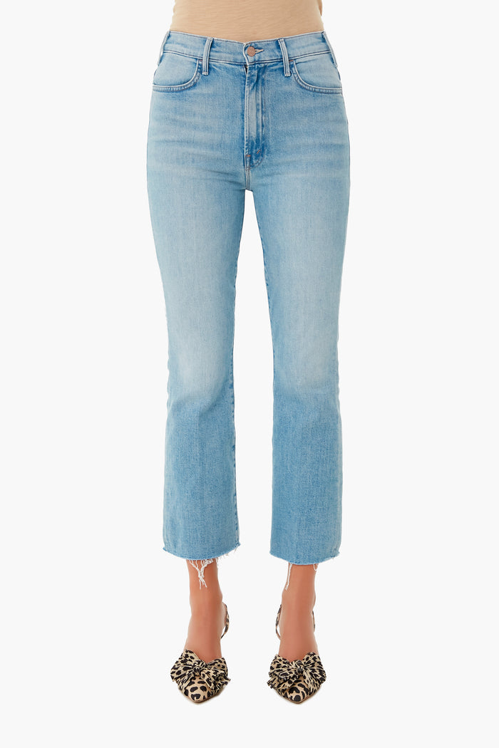 A person wears MOTHER light wash high-waisted cropped ankle jeans with a raw hem and animal print pointed-toe flats.