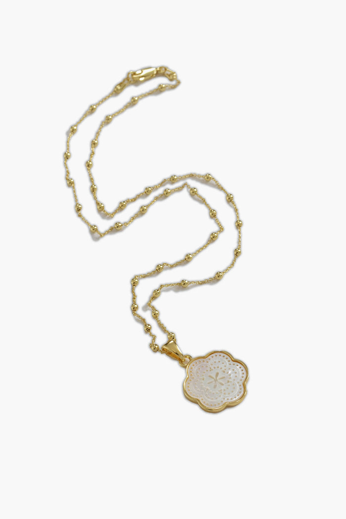 ASHA gold chain necklace featuring small beads and a flower-shaped white enamel mother of pearl pendant with an intricate pattern.