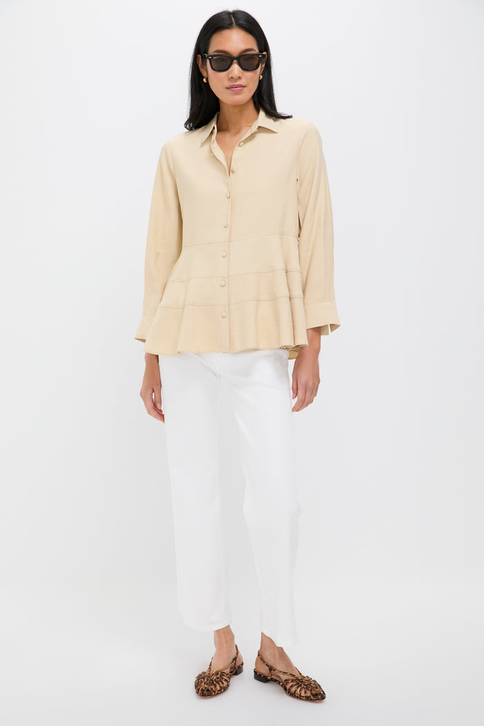 A woman wearing black sunglasses, a Pomander Place Tan Ashlen Blouse with a tiered hem, white pants, and leopard print flats stands confidently.
