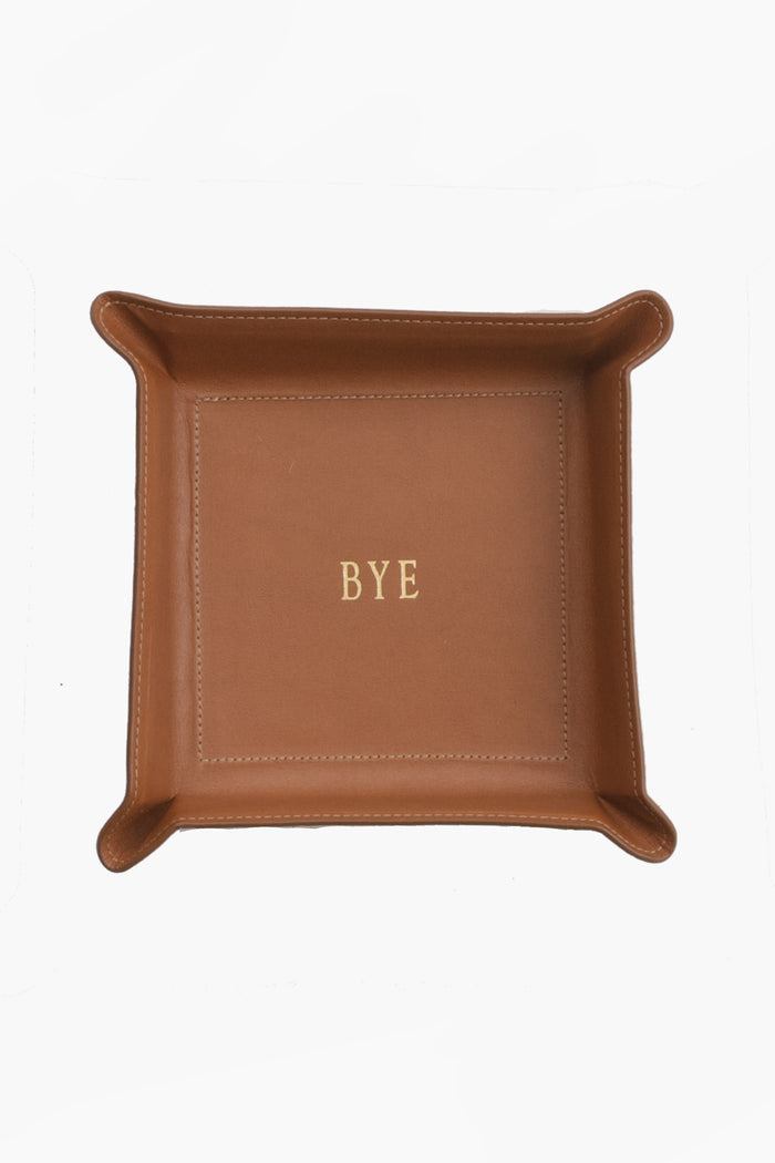 A brown Vachetta leather catchall tray by Graphic Image, featuring “BYE” embossed in gold at the center—ideal as a unique personalized gift.