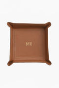 A brown Vachetta leather catchall tray by Graphic Image, featuring “BYE” embossed in gold at the center—ideal as a unique personalized gift.