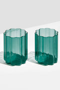 Two green, translucent scalloped tumblers by FAZEEK, crafted from hand-blown borosilicate glass, sit side by side on a white surface.