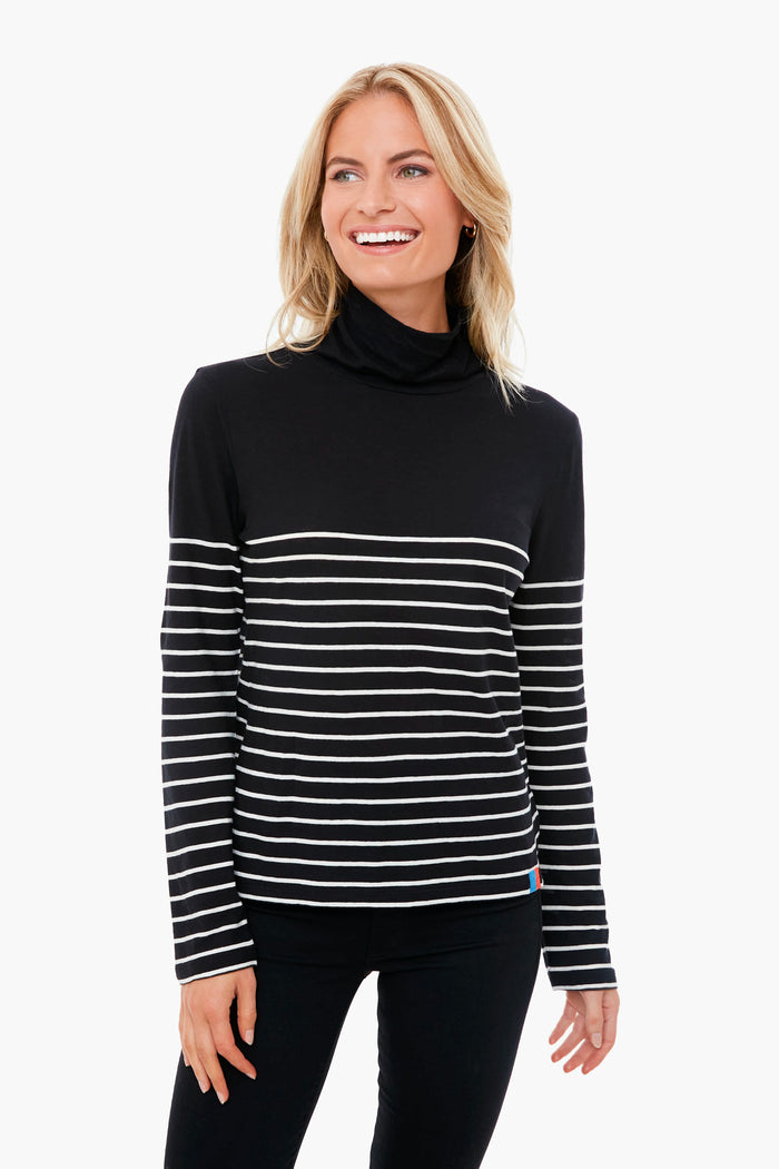 A woman smiles in a KULE striped turtleneck with white horizontal stripes, layered over a black tissue cotton tee.