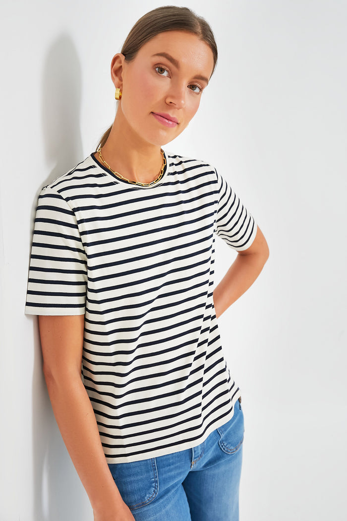 A person wears a KULE nautical stripe tee made from Portuguese cotton, styled with blue jeans, gold earrings, and a gold chain necklace.