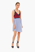 A woman wears a KULE stripe dress featuring a red and navy striped top and blue and white vertical striped skirt, paired with navy espadrille wedge sandals.