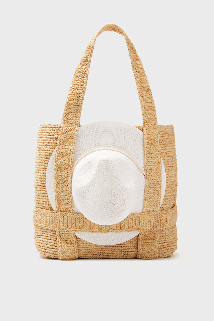 The Hat Attack woven straw traveling hat bag features two handles and a packable sunhat storage pocket attached to the front.