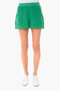 A person in a KULE stripe tee paired with green shorts and white sneakers creates a relaxed look.