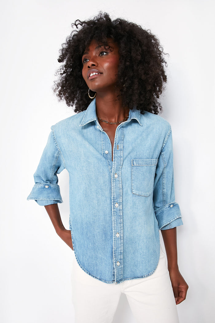 A person stands confidently in Citizens of Humanity chambray button down with rolled sleeves and white pants, showcasing a timeless style.