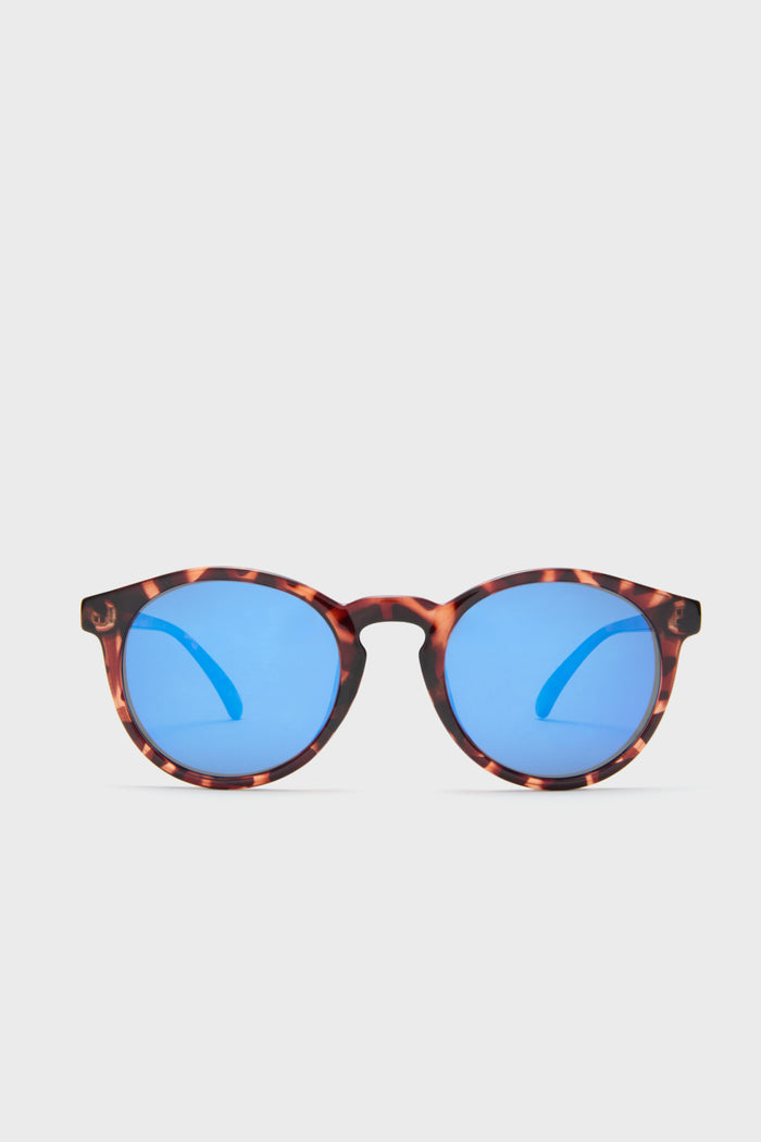 A pair of Sunski round tortoiseshell sustainable sunglasses with blue mirrored lenses is shown.