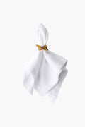 A white cloth napkin is held by a Juliska amber napkin ring, adding a touch of elegance and charm.