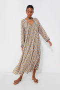 A woman stands gracefully wearing a Natalie Martin handmade batik long-sleeve dress and sandals.