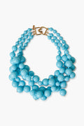 A chunky turquoise cluster necklace by Kenneth Jay Lane features three strands of large and small round beads with a gold clasp—an eye-catching piece of costume jewelry.
