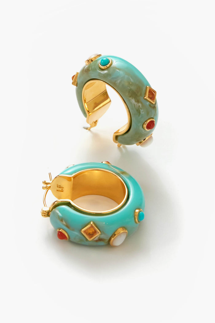 Lizzie Fortunato’s La Bomba Hoops are chunky, gold-plated brass earrings adorned with colorful gem-like stones in red, green, white, and amber accents.