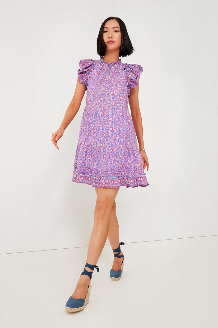 A woman confidently walks in a Vineyard Vines dress with ruffled sleeves and blue wedge sandals.