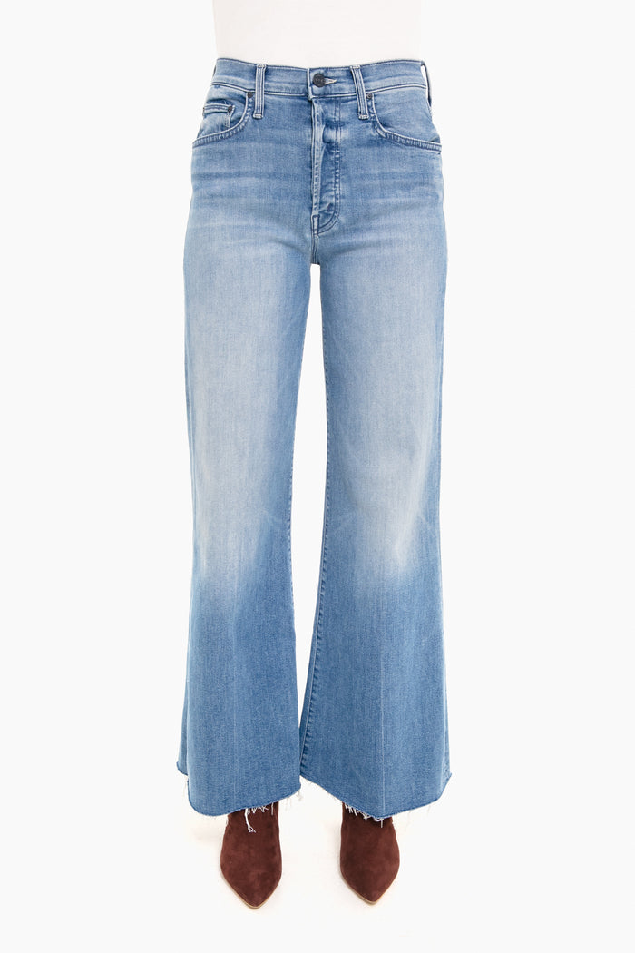 A person shown from the waist down wearing MOTHER high-rise wide-leg jeans with a frayed hem and brown pointed-toe shoes.
