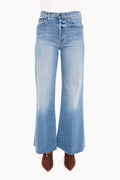 A person shown from the waist down wearing MOTHER high-rise wide-leg jeans with a frayed hem and brown pointed-toe shoes.