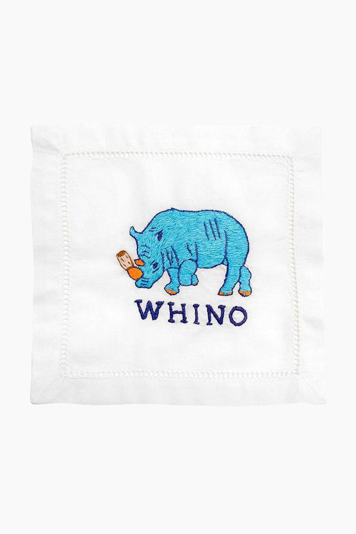 A blue embroidered rhinoceros holding a wine glass stands above “WHINO” on a white linen cocktail napkin by August Morgan—an ideal hostess gift.