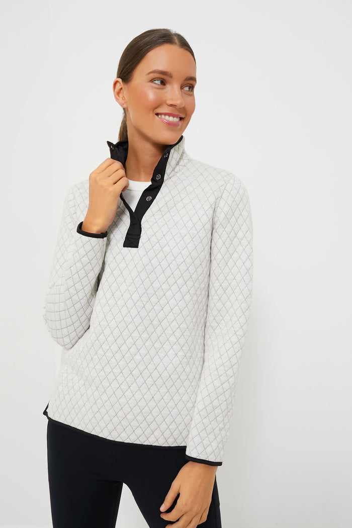 A woman in a light grey Marine Layer eco-friendly pullover with black trim looks to the side with a slight smile.
