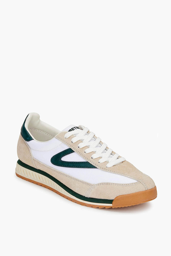 The Tretorn women's sneaker features beige, white, and dark green canvas in a low-top retro design with white laces and a textured gum sole.