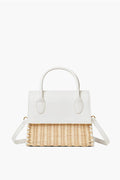 The Urban Expressions handbag features a white leather top, handles, and flap, paired with a woven straw bottom and an adjustable shoulder strap.
