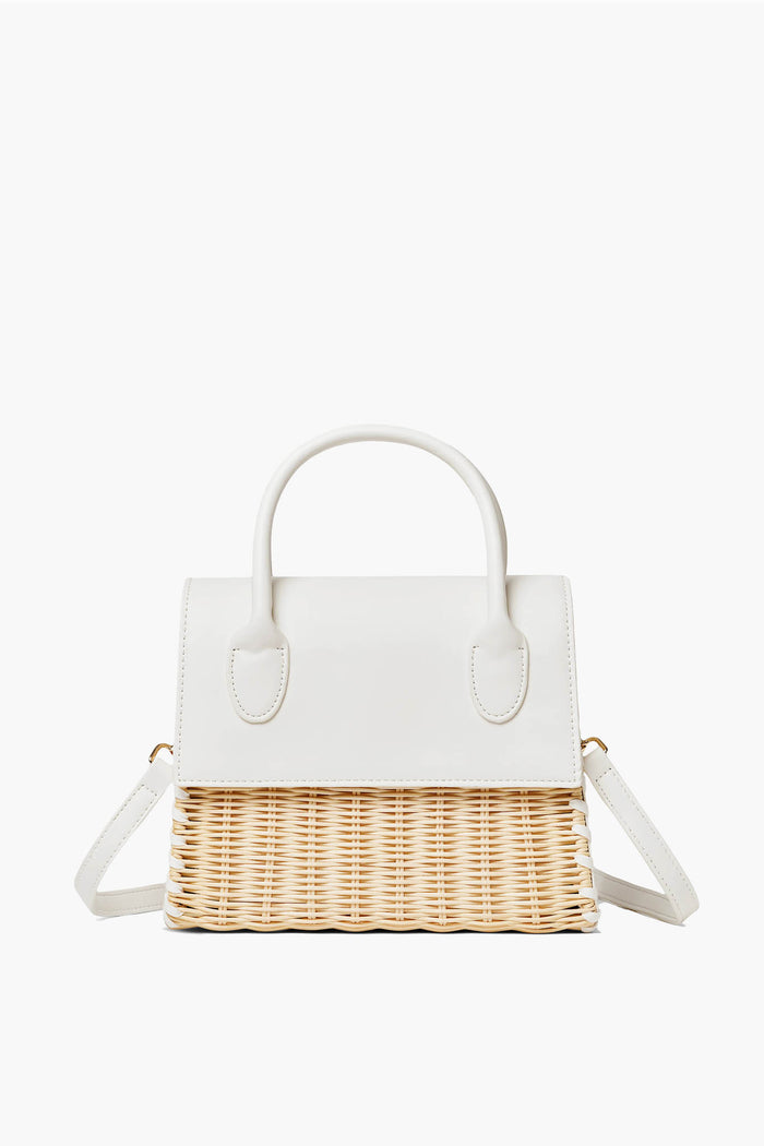 The Urban Expressions handbag features a white leather top, handles, and flap, paired with a woven straw bottom and an adjustable shoulder strap.