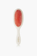 A Mason Pearson luxury hairbrush is shown, featuring a white handle, red cushioned base, and white bristles.