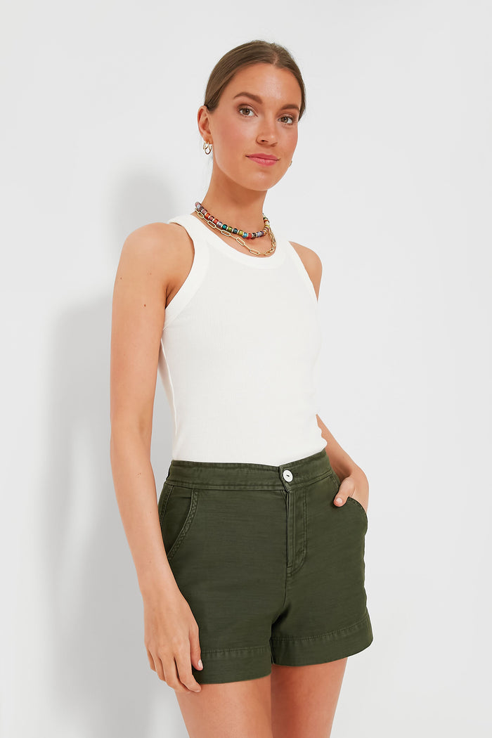 A woman wears an Alex Mill white ribbed cotton tank, olive green shorts, and a colorful beaded necklace.