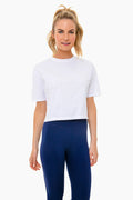 A woman wears Addison Bay’s white short sleeve cropped tee with navy blue high-waisted leggings—an ideal activewear outfit.