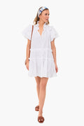 A woman wears the Hunter Bell Merritt Dress, a white cotton poplin ruffled mini dress.