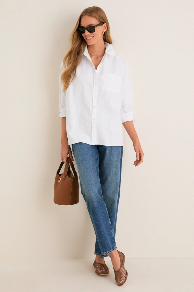 Woman in a classic, effortless White Oxford Adair Boyfriend Shirt with bracelet-length sleeves, styled with jeans and accessories, embodying Tuckernuck's fun, high-end aesthetic.