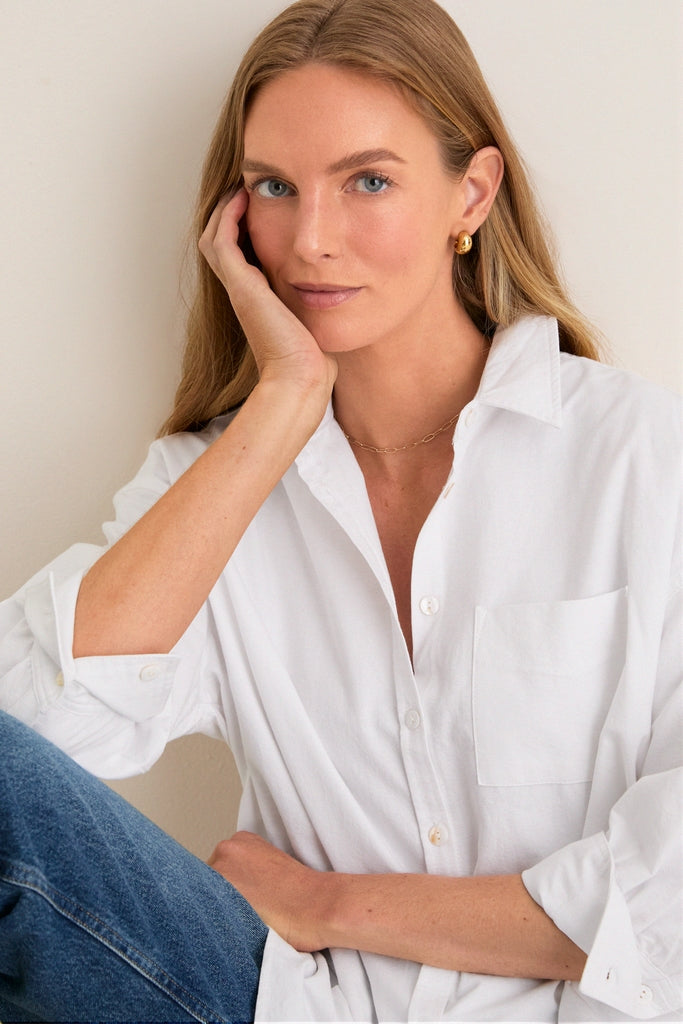 Young woman in a classic, effortless White Oxford Adair Boyfriend Shirt with rolled sleeves, embodying a fun, high-end style, perfect for versatile, seasonless wear.