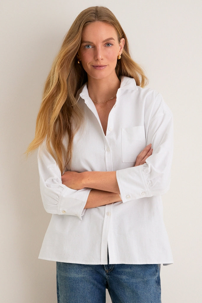 Woman wearing the classic White Oxford Adair Boyfriend Shirt with effortless bracelet-length sleeves, embodying fun and high-end style, perfect for versatile, seasonless wardrobe pairings.