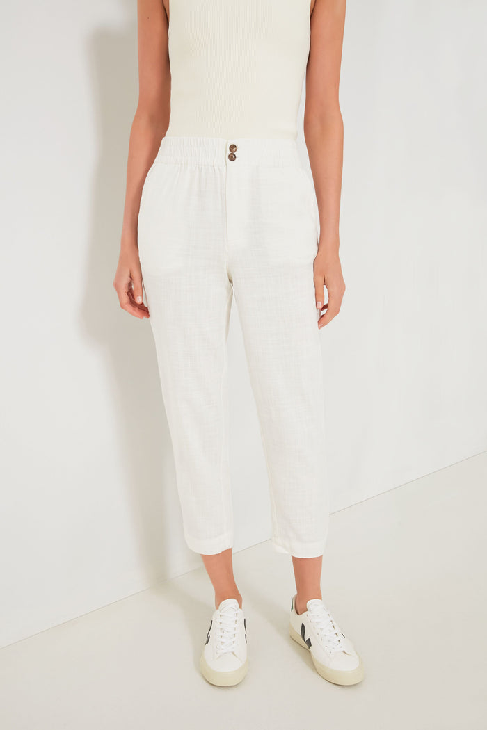A person wears a Marine Layer sleeveless white top, ultra-soft white trousers with an elastic waistband and buttons, and white sneakers for a fresh, casual look.