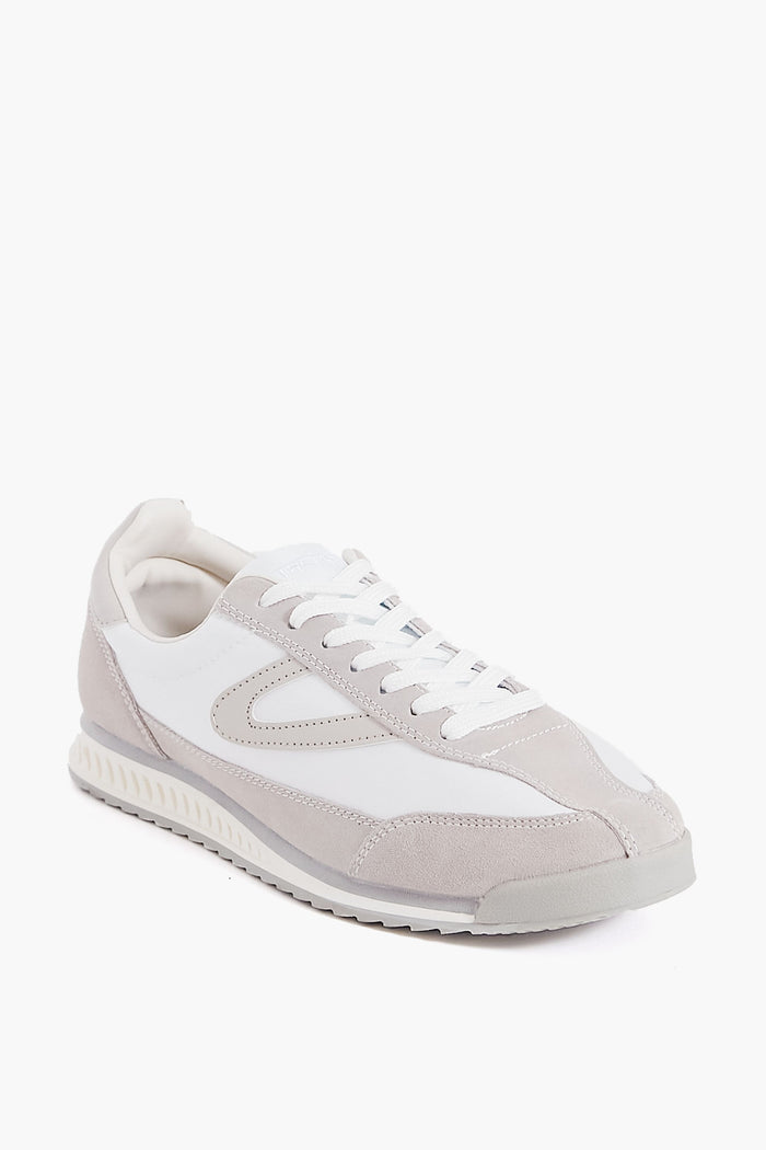 A Tretorn Rawlins 2.0 sneaker in white, featuring white laces, a textured sole, and suede and leather panel details, is pictured at a three-quarter angle.