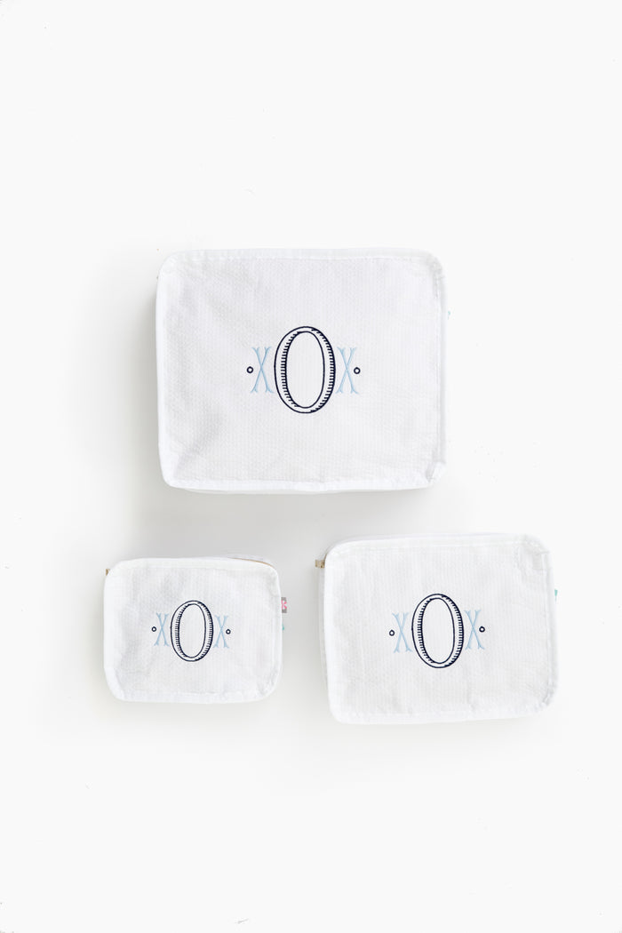 Three white seersucker travel pouches by Caton's Wharf, each in a different size with a large embroidered letter O and blue accents—ideal as a bridesmaids gift.