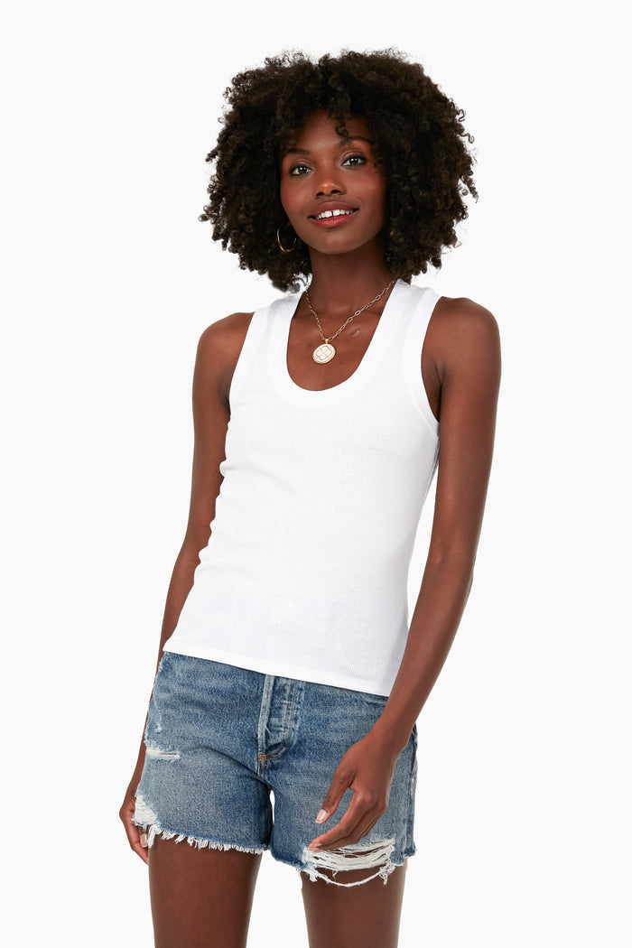 A woman stands confidently in a Z SUPPLY slim fit Sirena Tank in white, crafted from feather rib fabric, paired with distressed denim shorts.