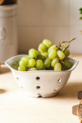 A cluster of green grapes sits in a Farmhouse Pottery, Inc white berry bowl on a light countertop.