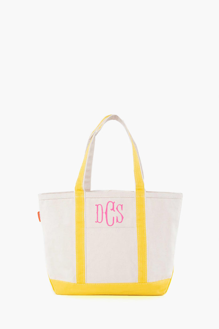 The CB Station beige canvas tote bag features yellow handles and trim, plus pink DCS monogram initials on the front. This stylish, reusable bag is ideal for everyday use.