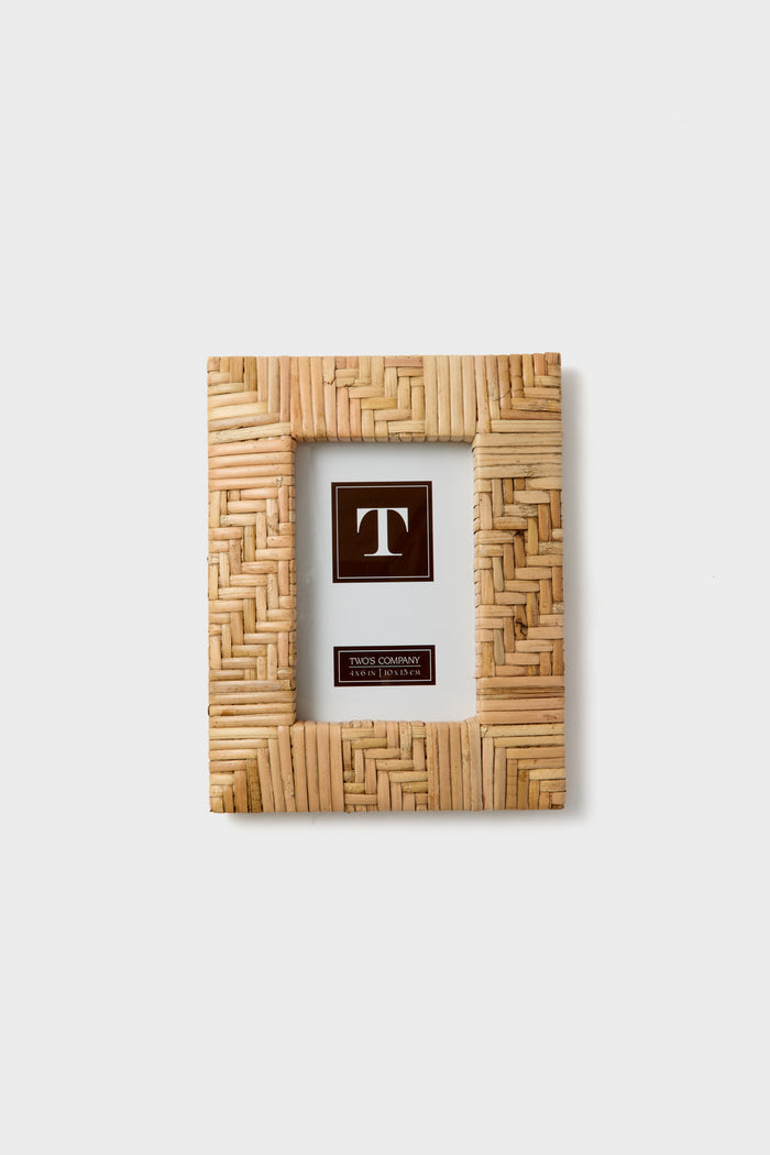 The Two's Company rectangular picture frame features woven light brown wood, making it ideal for boho home decor or a thoughtful housewarming gift.